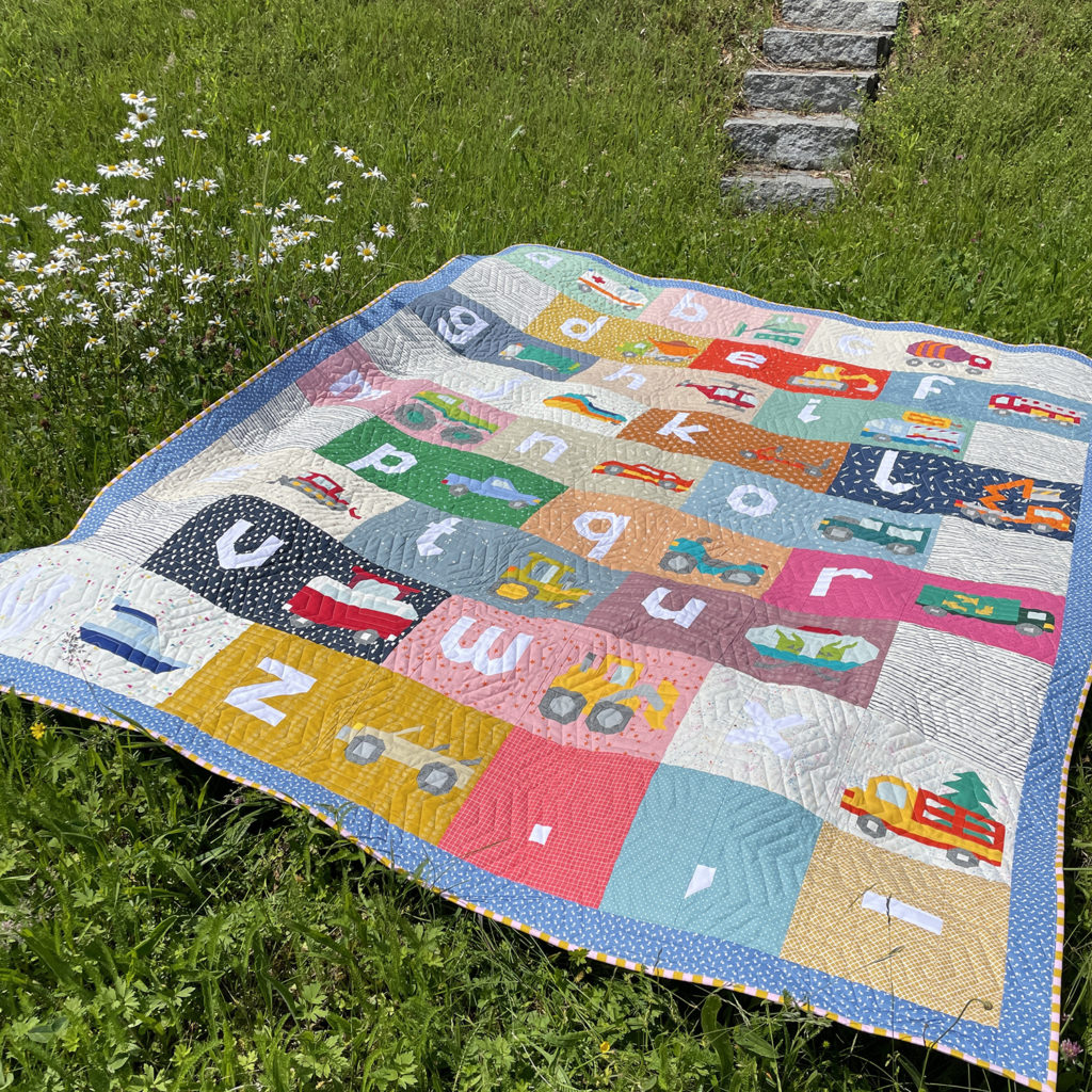 Letter-Vehicle Quilt auf einer grünen Wiese liegend