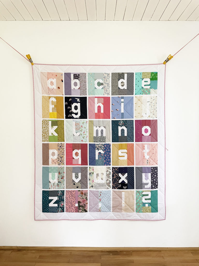 kompletter Scrappy Letter Quilt avor weißer Wand hängend