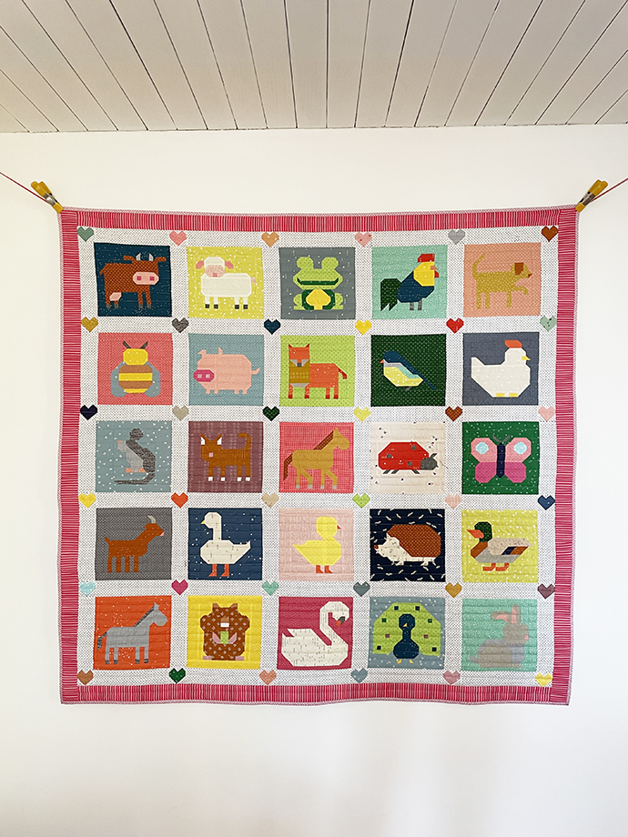 Kompletter Animal Quilt hängt mit Klammern befestigt vor einer weißen Wand