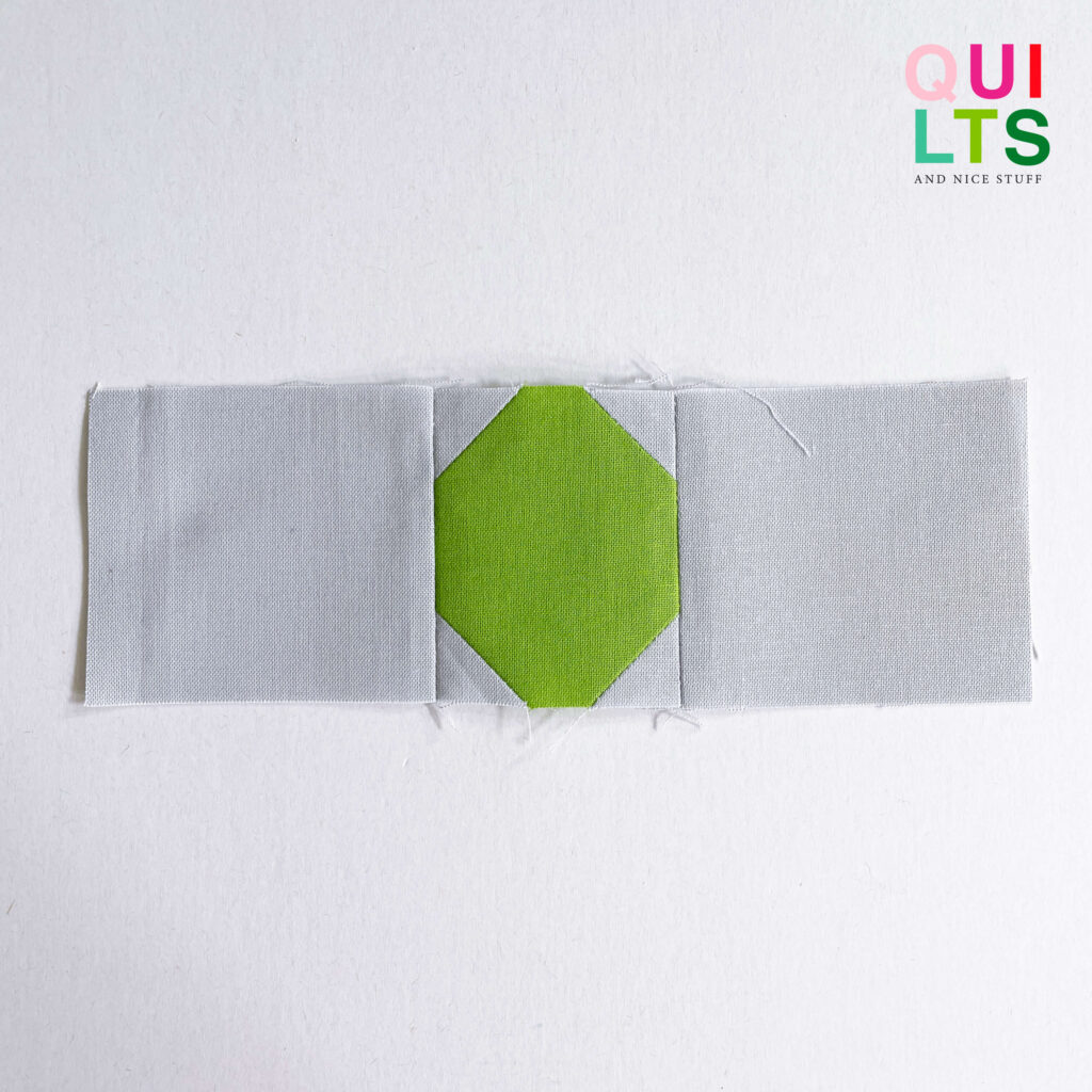Schritt für Schritt Anleitung. Das Bild zeigt einen Schritt für das Nähen eines Straßen Quilt Blocks, einer Sackgasse mit Grün, es zeigt Stoffteile auf weißem Hintergrund.